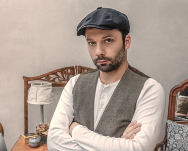 Man mit grauer Schiebermütze und Weste